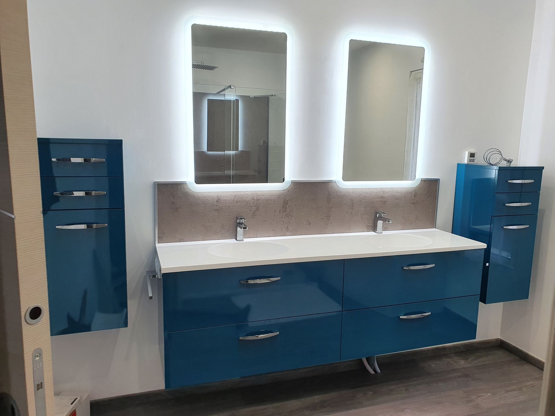 Meuble-lavabo moderne avec armoires bleues, double vasque, miroirs et armoires de rangement murales.