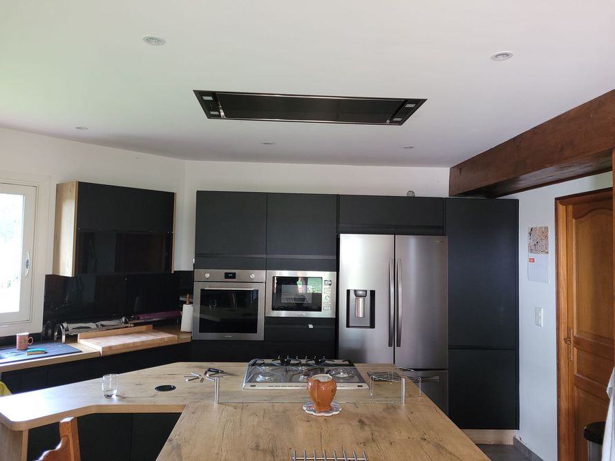 Cuisine moderne avec armoires foncées, appareils électroménagers en acier inoxydable et ouverture au plafond non finie.