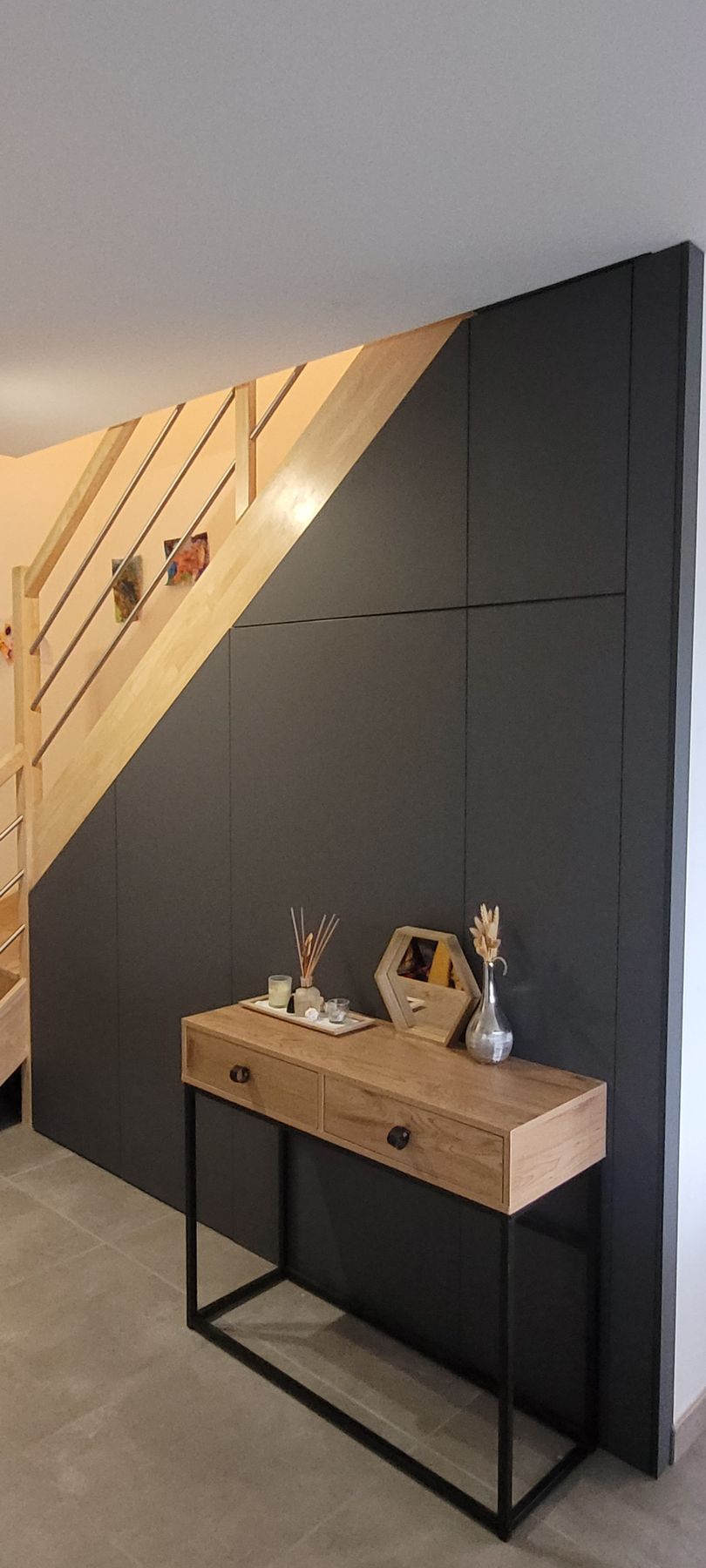 Couloir moderne avec placards encastrés foncés, une petite console en bois et un escalier à l'éclairage chaleureux