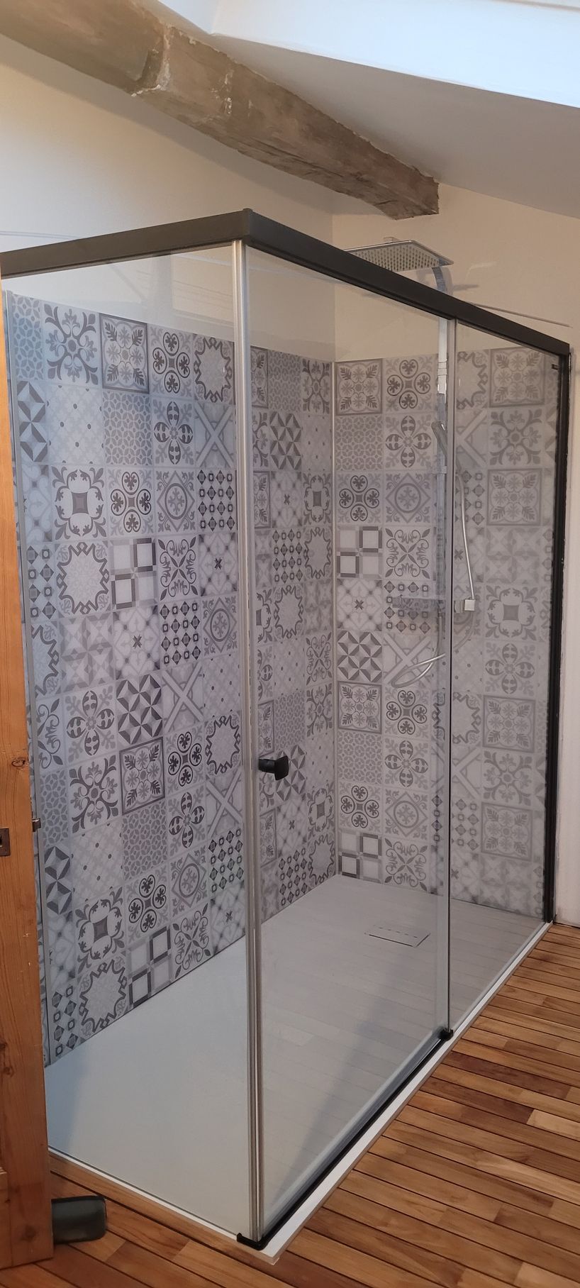 Cabine de douche moderne en verre avec murs carrelés à motifs et plafond mansardé dans une salle de bain de type loft