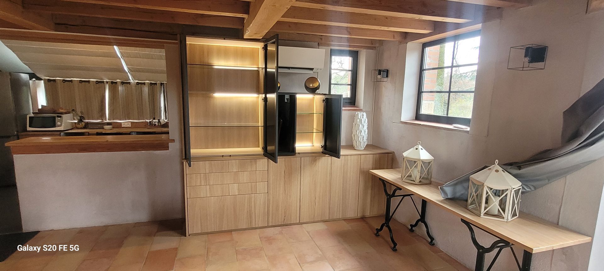 Cuisine moderne avec placards en bois, four encastré, fenêtre et table pliante contre le mur.
