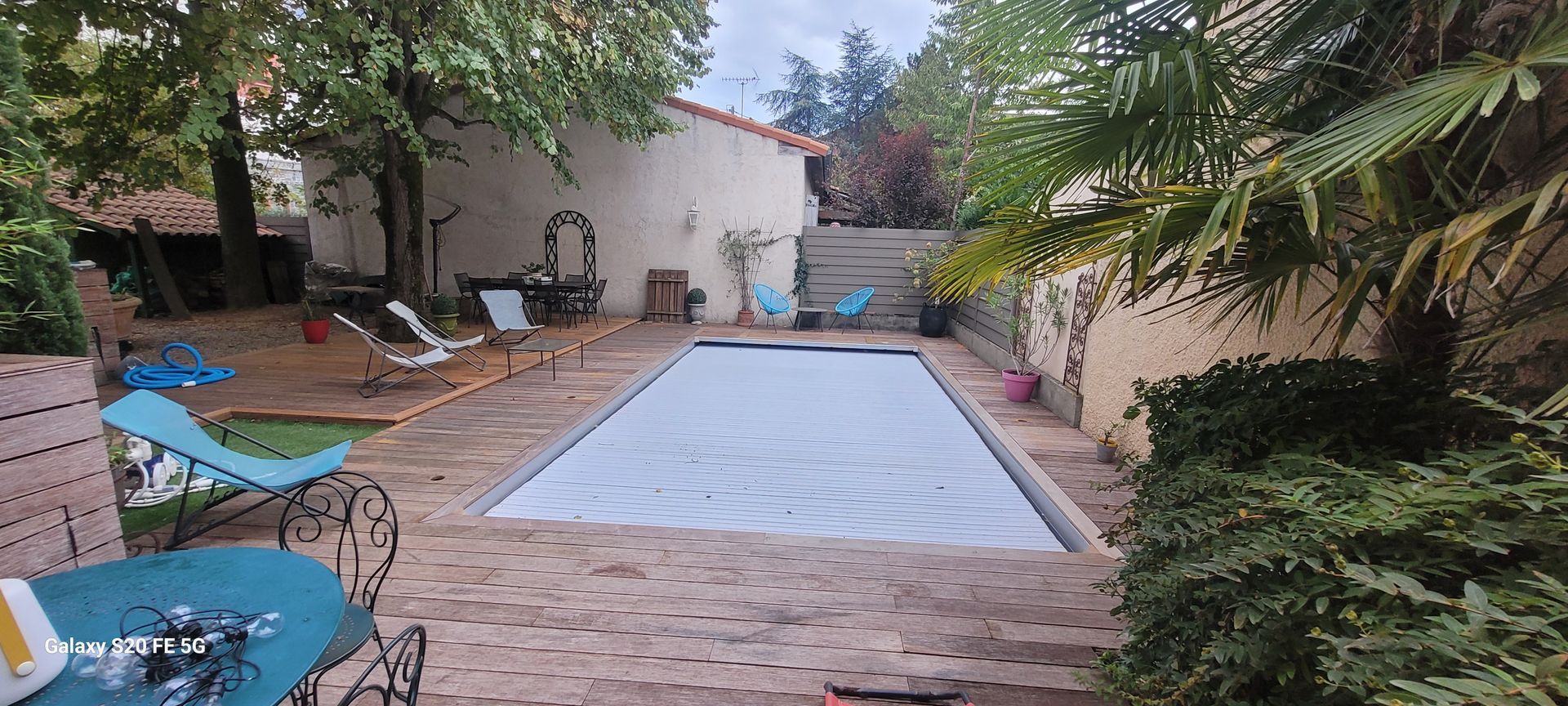 Terrasse arrière avec piscine rectangulaire, chaises longues et plantes le long du chemin de briques