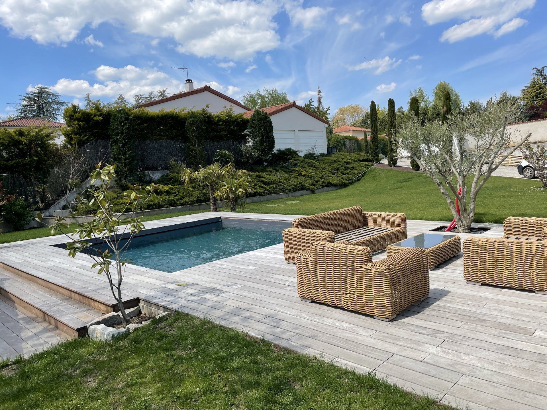 Terrasse en bois aménagé autour d'une piscine, avec salon de jardin extérieur.