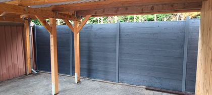 Vor einem Haus mit vielen Fenstern wird eine Terrasse gebaut.