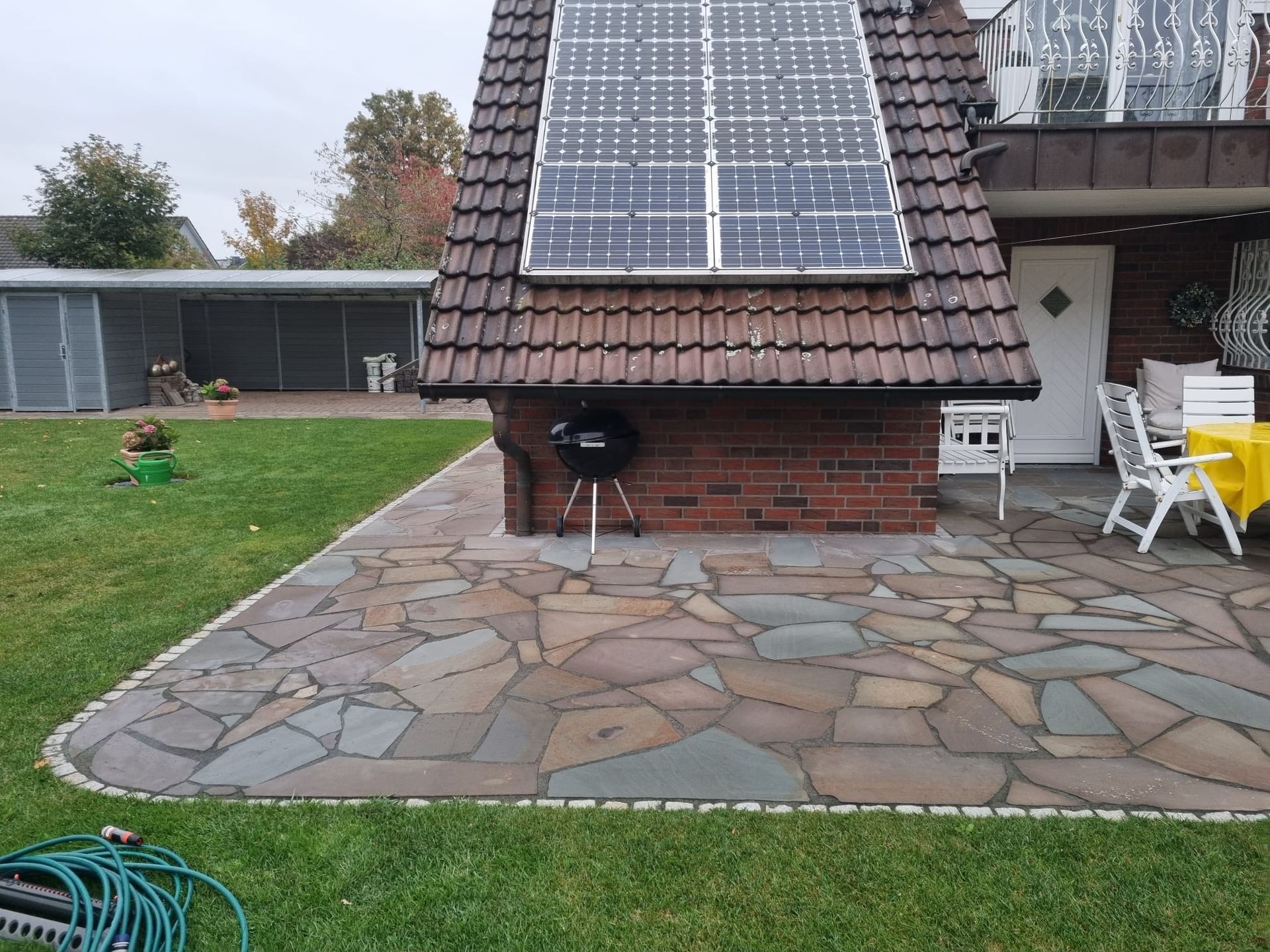 Ein Haus mit einer Solaranlage auf dem Dach und einer Terrasse mit Grill.
