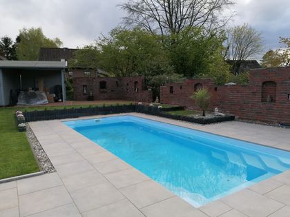 Ein Backsteinhaus mit einer Terrasse und einer Pergola davor.