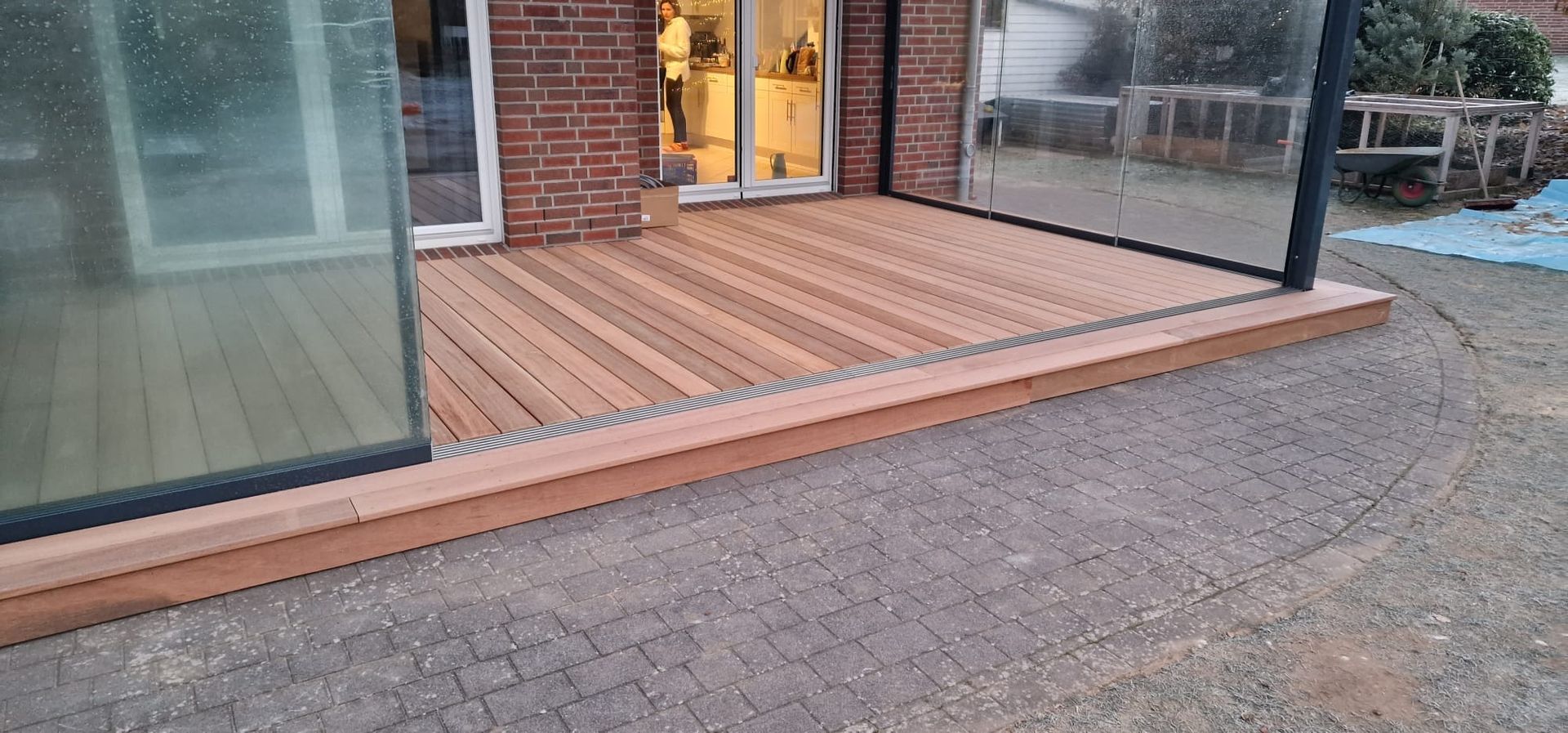 Vor einem Backsteinhaus befindet sich eine Holzterrasse.