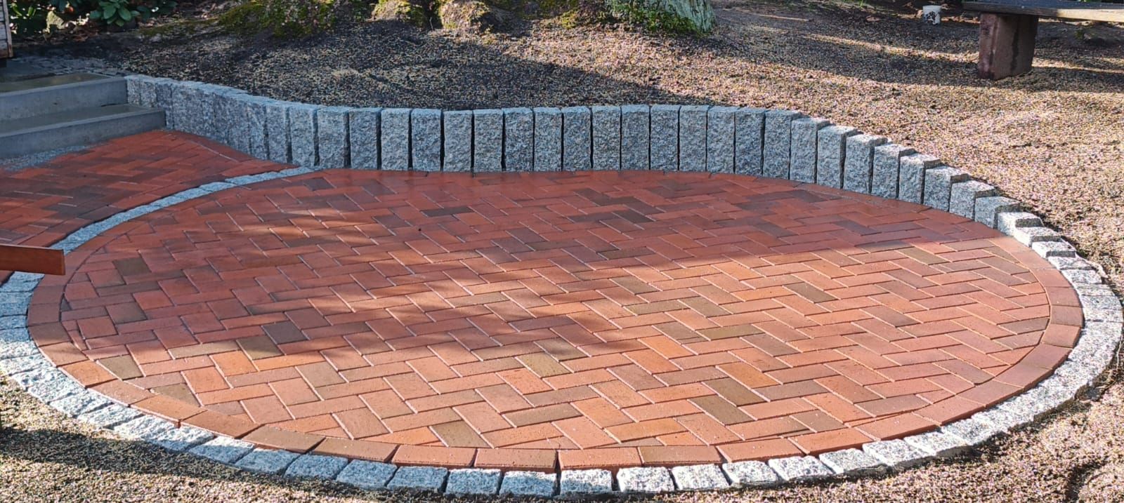 Ein kreisförmiger Ziegelweg mit einer Bank im Hintergrund
