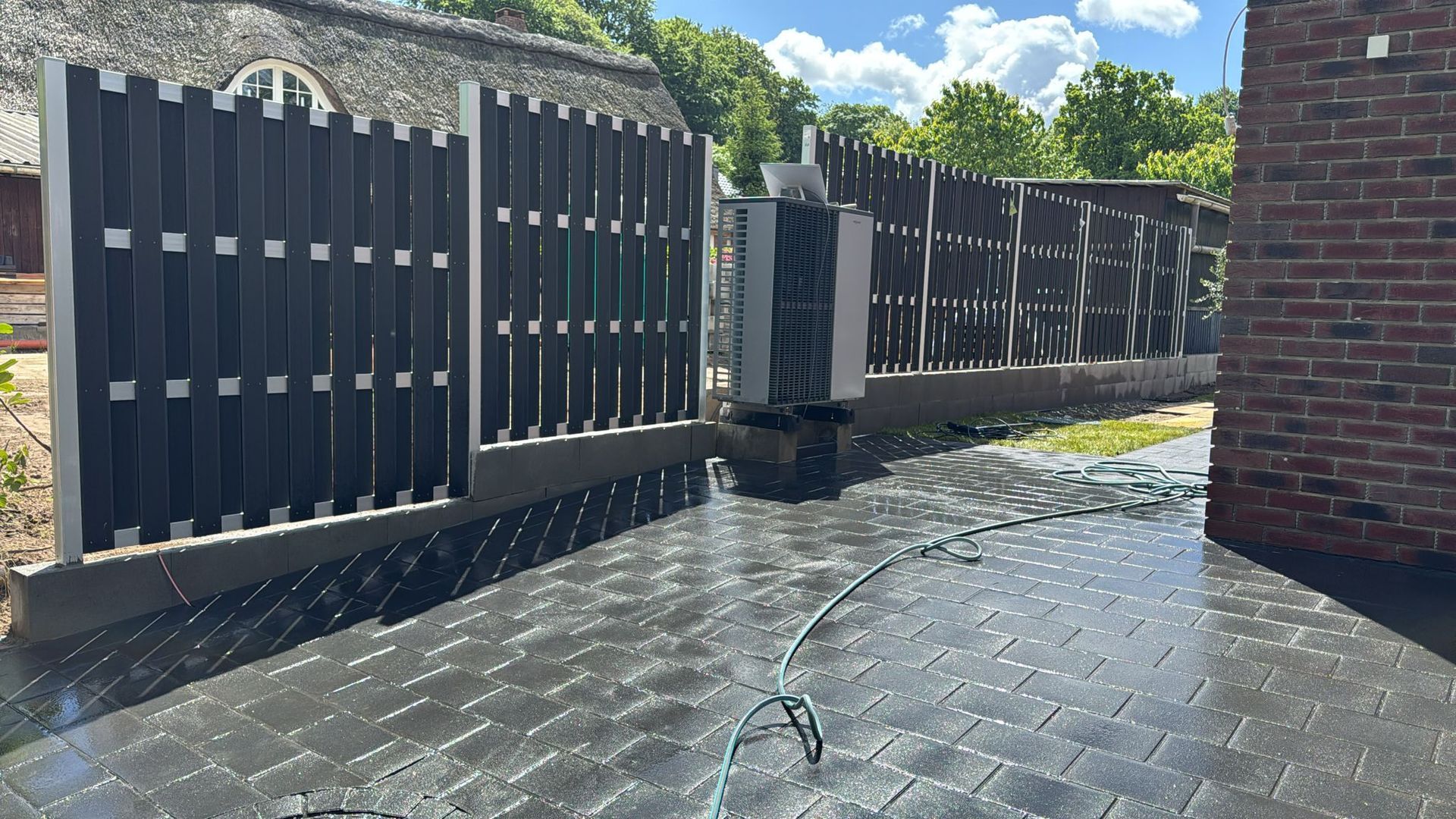 Ein Backsteingebäude mit einem schwarzen Zaun und einem Schlauch davor.