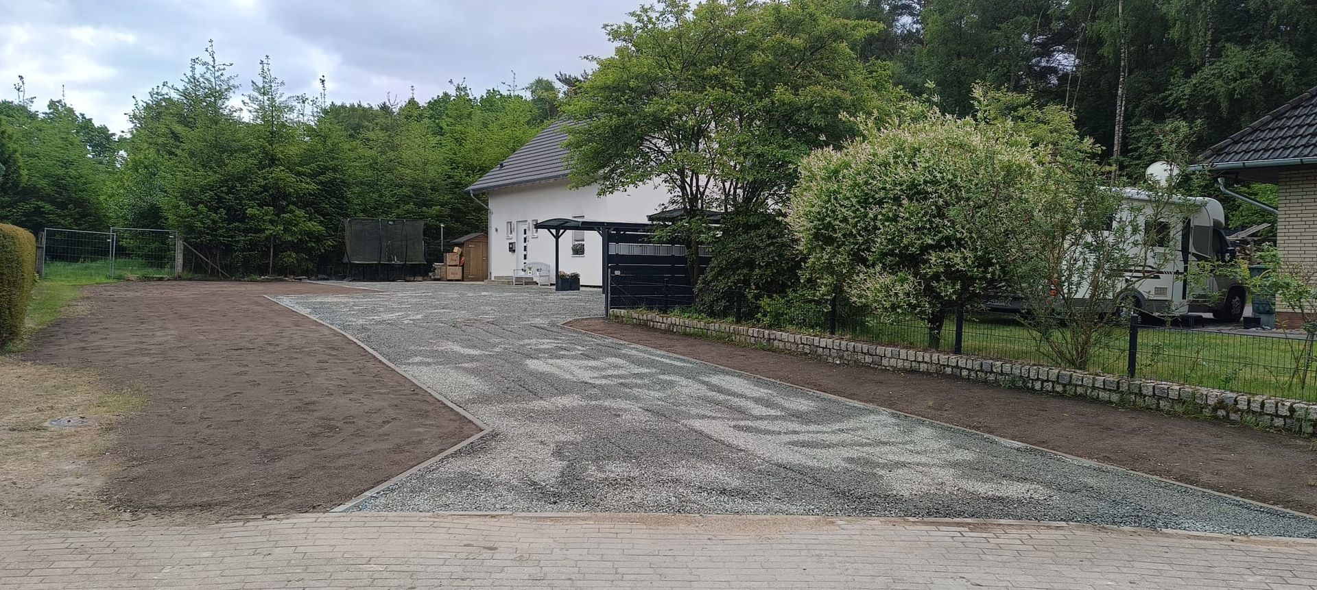 Ein Feldweg führt zu einem Haus mit Bäumen auf beiden Seiten.