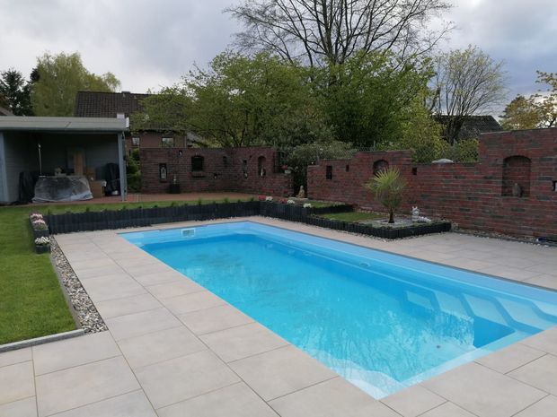 Im Hinterhof eines Hauses befindet sich ein großer Swimmingpool.