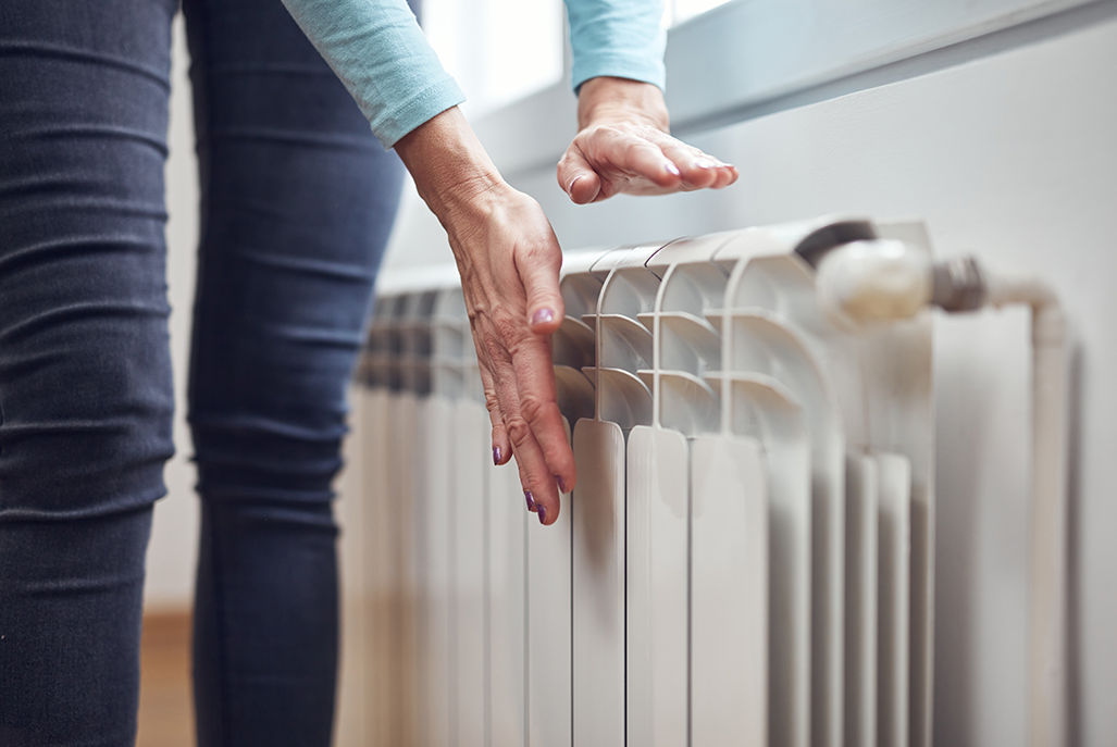 Femme chauffant ses mains sur le radiateur pendant les froides journées d'hiver.