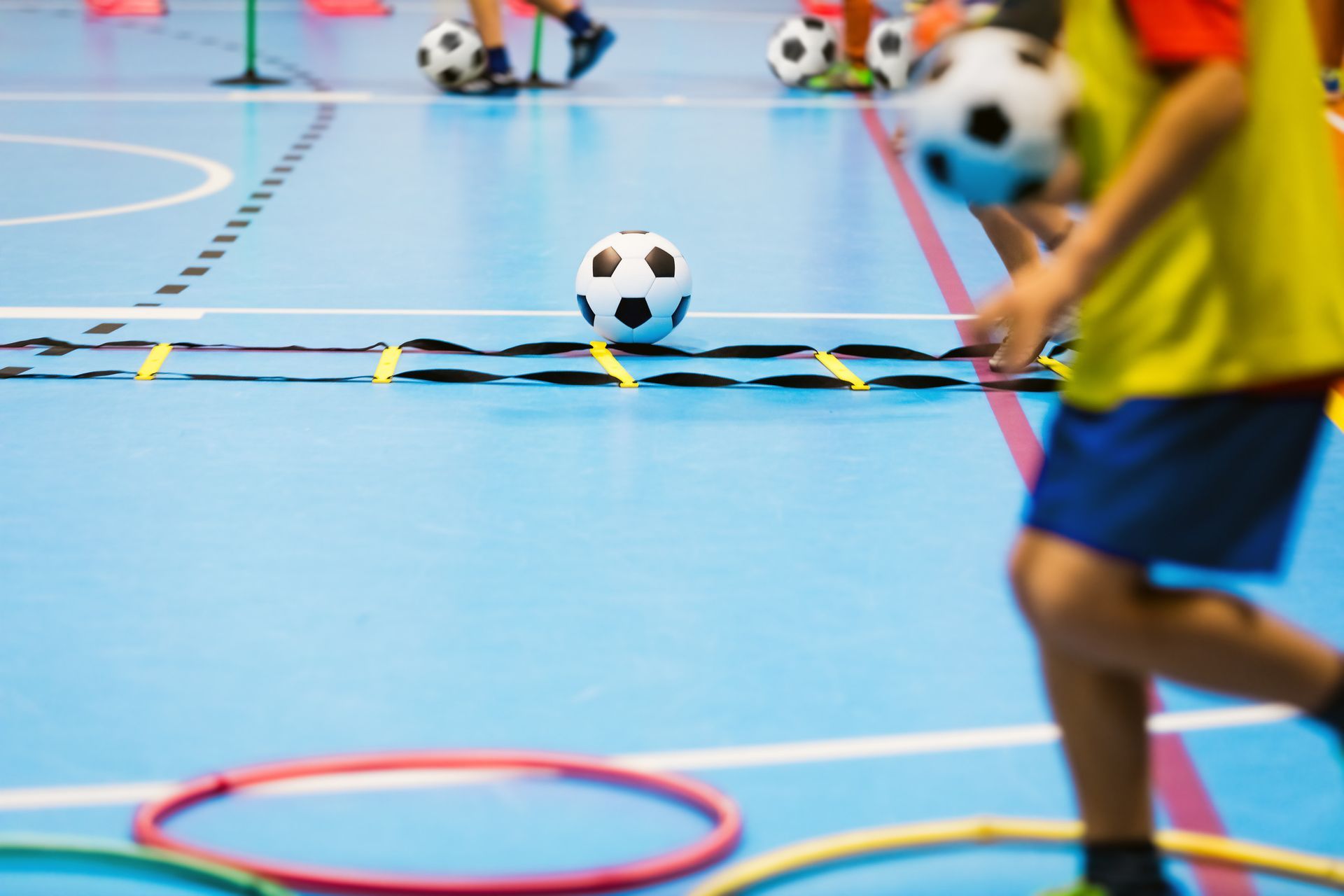 Un grupo de niños está jugando fútbol en un gimnasio.