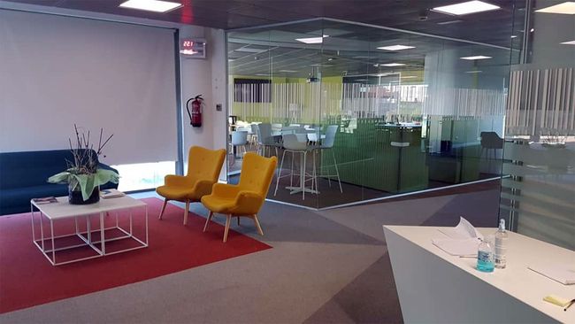 Una sala de conferencias con una mesa, sillas, computadoras portátiles y una pantalla de proyector.