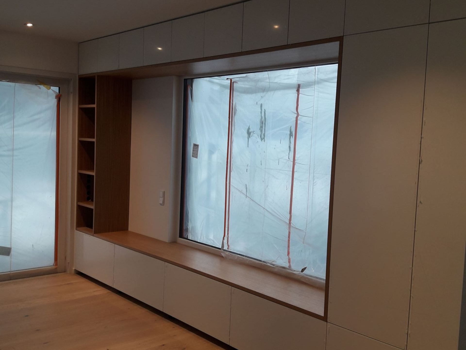 Einbauschränke mit Fensterbank und Regalen. Helles Holz und weiße Oberflächen. Inneneinrichtung.