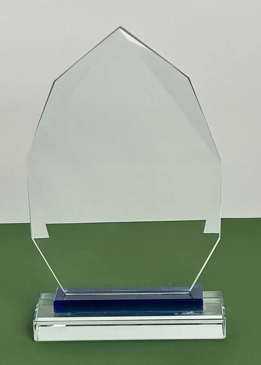 Un trofeo de cristal transparente con una base azul está sobre una mesa verde.
