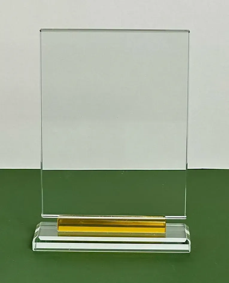 Una placa de vidrio transparente con una base dorada se encuentra sobre una mesa verde.