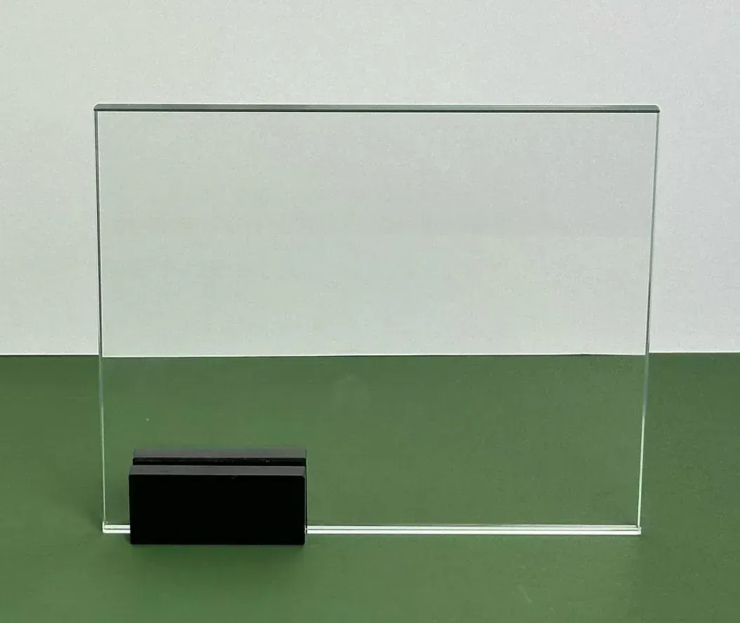 Una placa de vidrio transparente con una base negra está sobre una mesa verde.