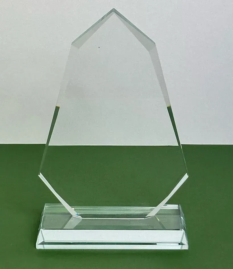 Un trofeo de cristal transparente está sobre una mesa verde.