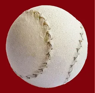 Un primer plano de una pelota de béisbol blanca sobre un fondo rojo.