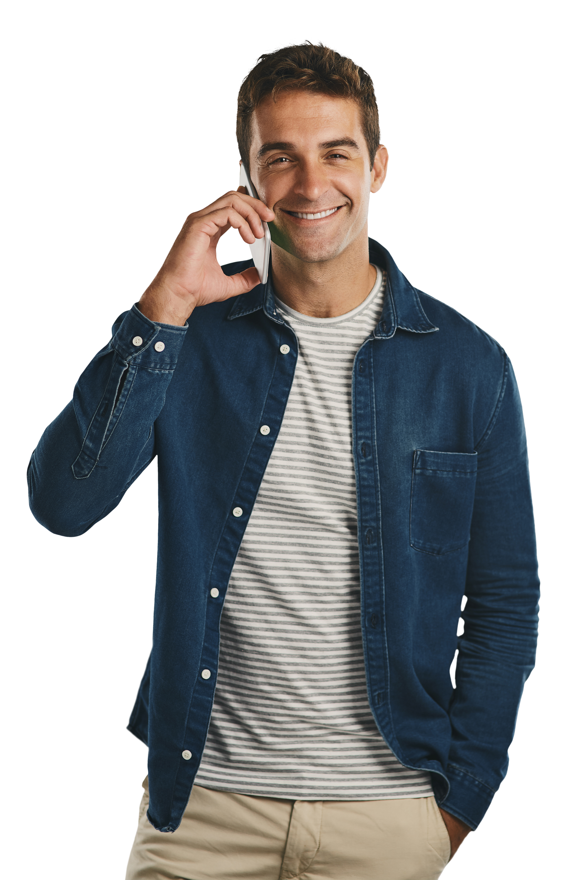 Un homme souriant, parlant au téléphone, portant une chemise en jean par-dessus une chemise rayée et un pantalon beige.