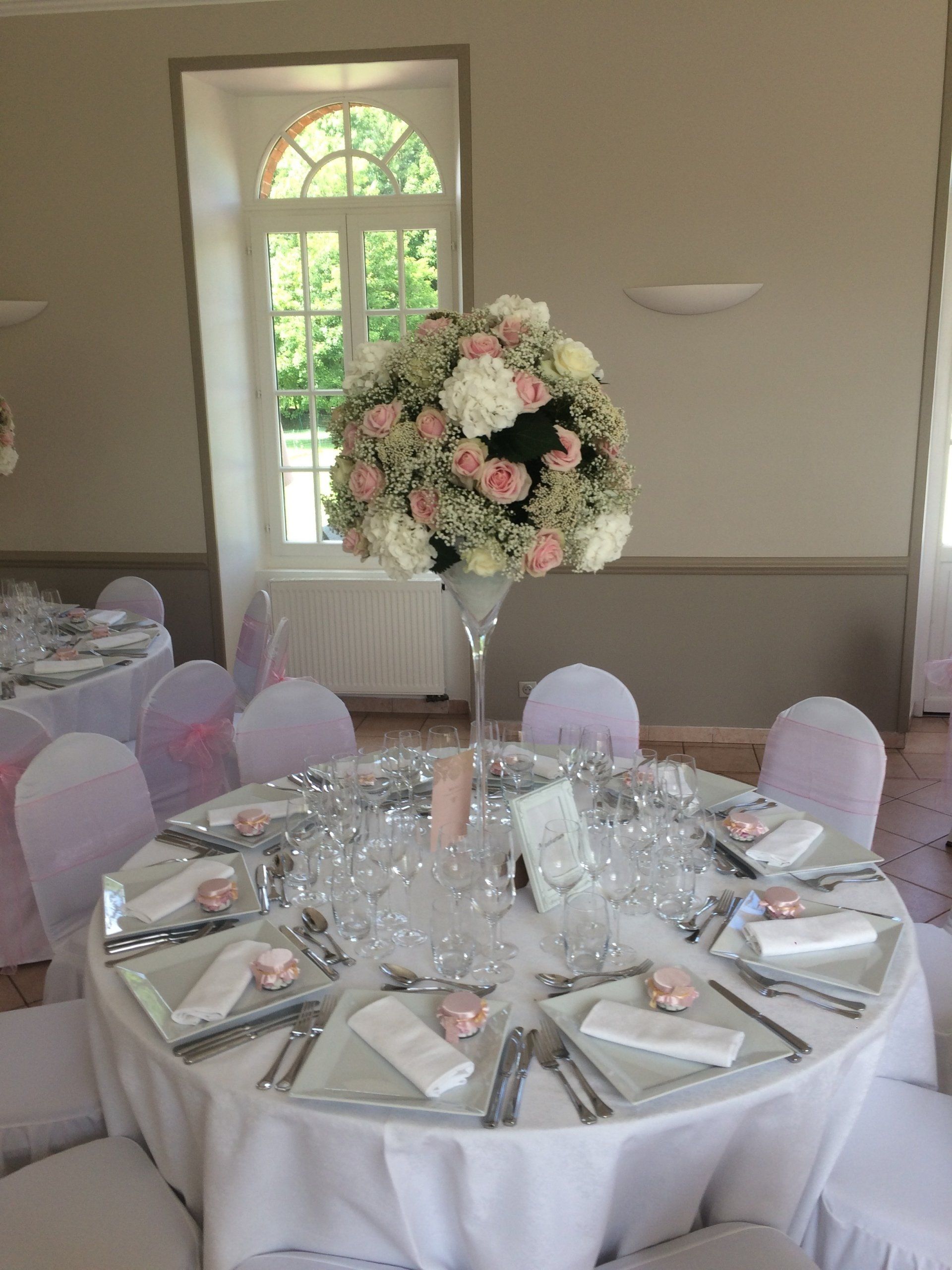 Décoration d'une table ronde pour un évènement avec un bouquet de fleurs blanches et roses pâles