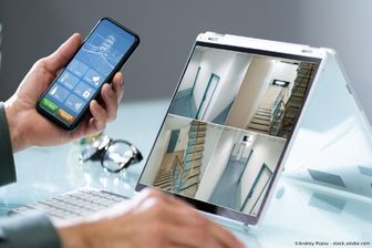 S.C. Elektro UG (haftungsbeschränkt) Person schaut auf einen Bildschirm und hat ein Handy in der Hand