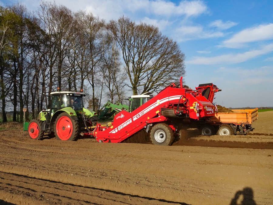 Ein grün-roter Traktor pflügt ein Feld.