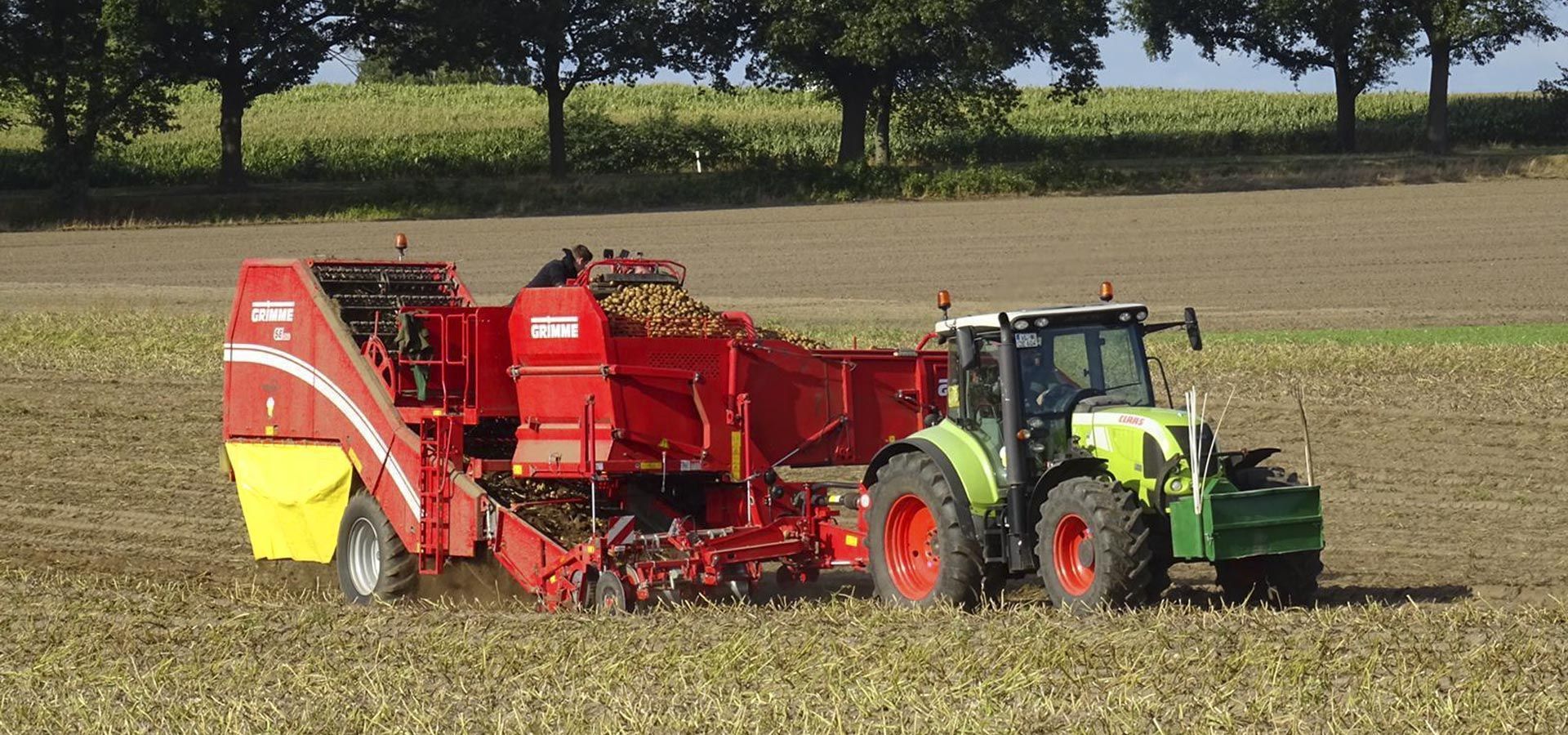 Ein grün-roter Traktor pflügt ein Feld