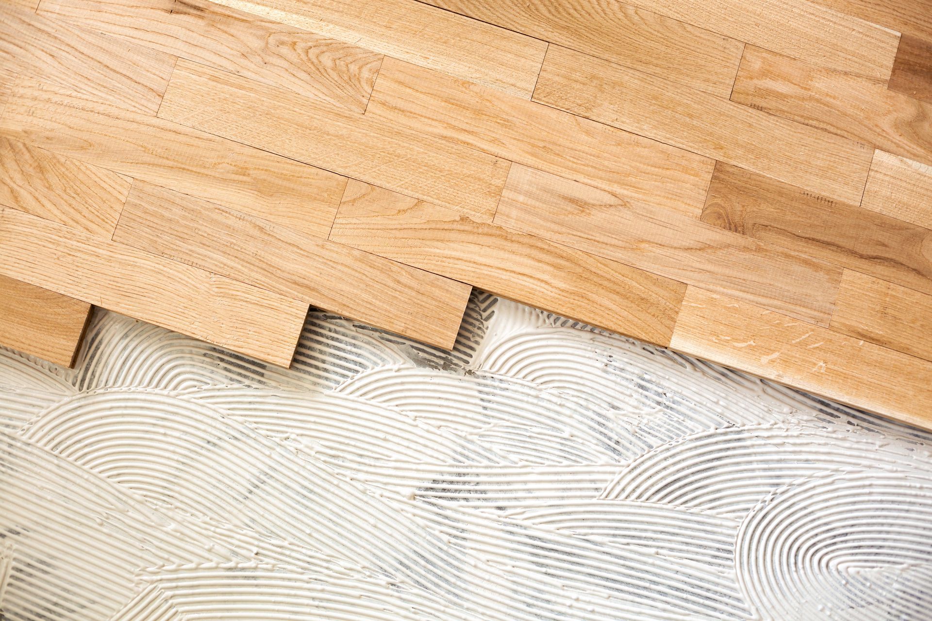 Les planches du plancher en bois sont partiellement soulevées pour révéler une sous-couche blanche.