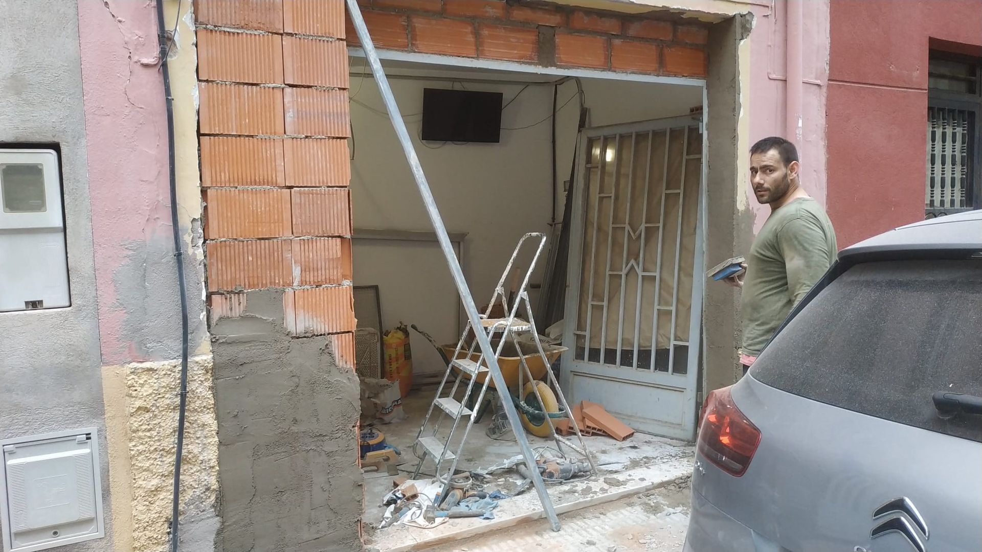 Un hombre está parado frente a una puerta de garaje que está abierta.