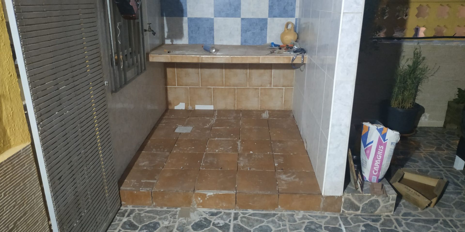 Una pequeña habitación con suelo de baldosas y una pared de ladrillo.