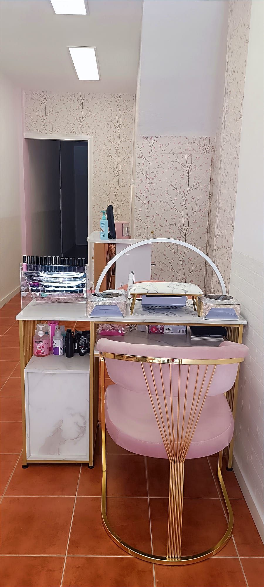 Un salón de uñas con una silla rosa y una mesa.