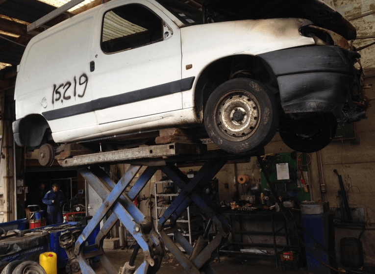 Phare de voiture embué nécessitant un polissage, avec l'inscription « Lustrage d'optique » visible.