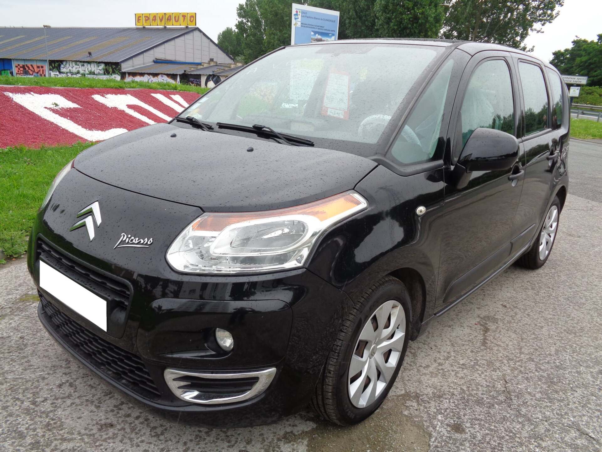 Citroën C3 Picasso noire garée sur le trottoir.