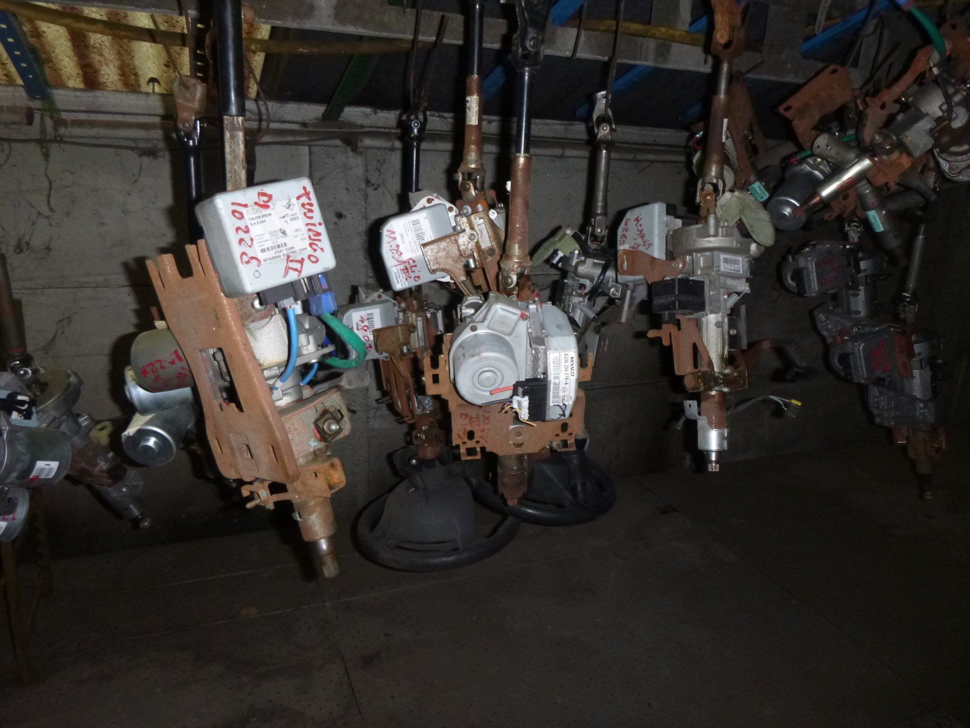 Des colonnes de direction suspendues dans un espace de stockage encombré, avec des composants mécaniques.