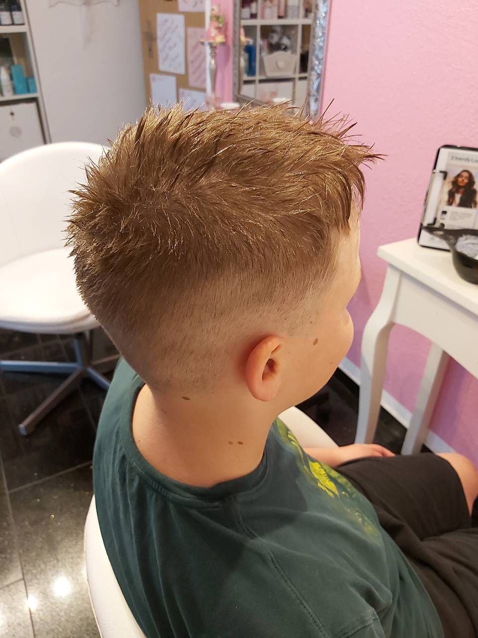 Ein kleiner Junge sitzt auf einem Stuhl. Sein Haar ist mit Glitzer bedeckt. BM Hair and Beauty