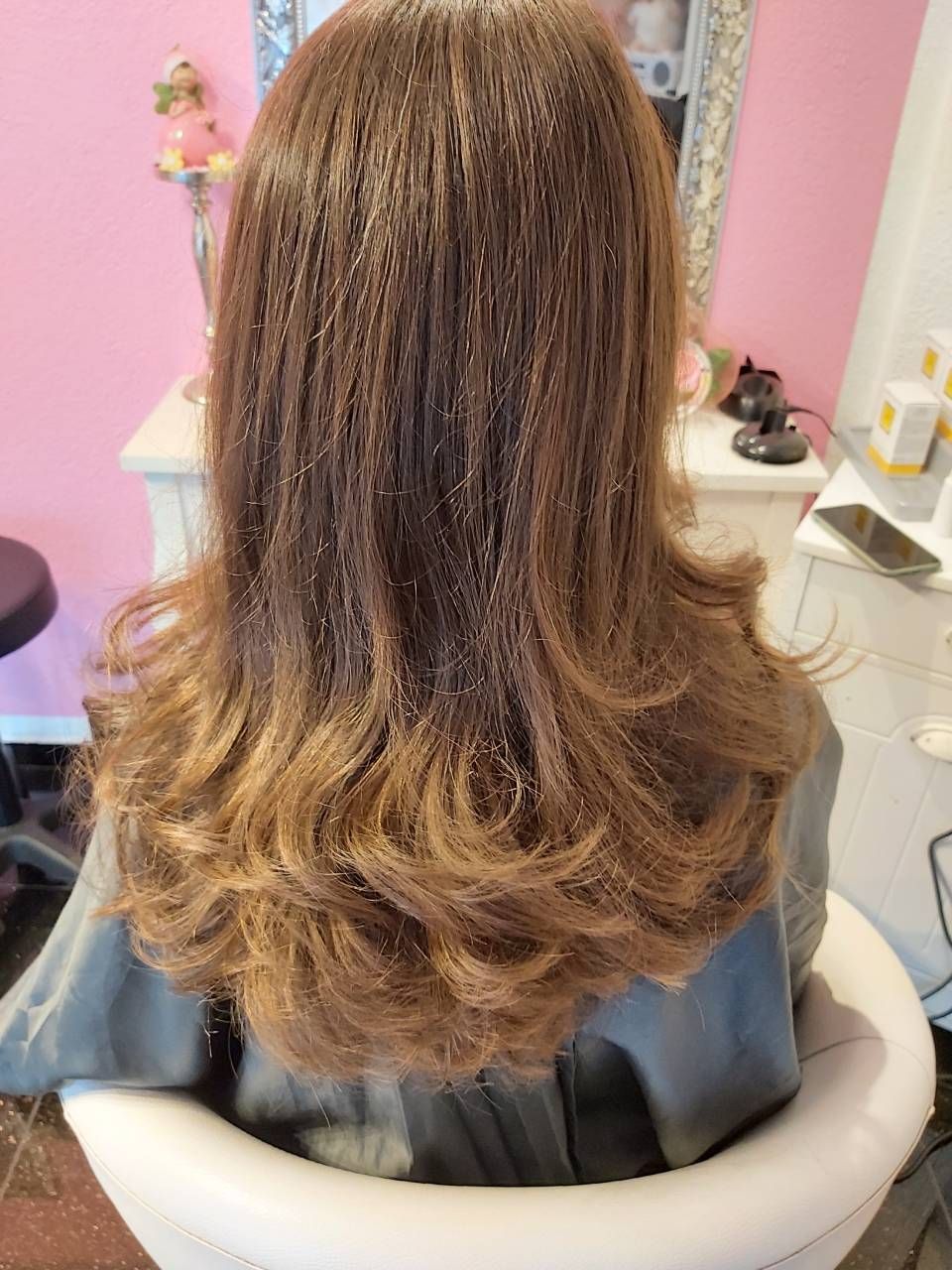 Eine Frau sitzt auf einem Stuhl und hat ihr Haar in einer Schüssel. BM Hair and Beauty