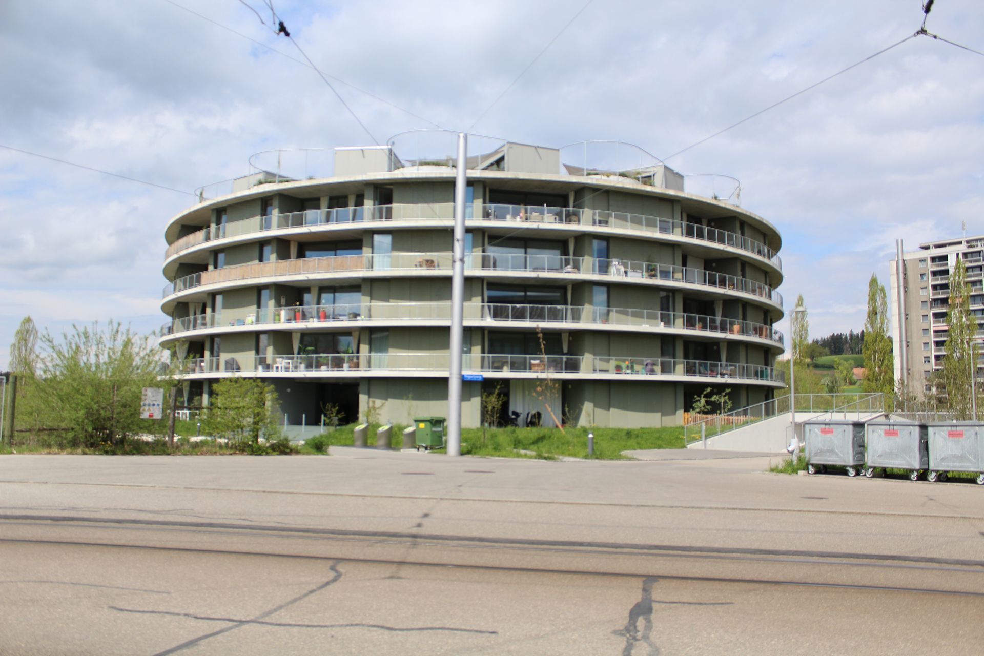 Ein großes Gebäude mit vielen Balkonen steht am Straßenrand.