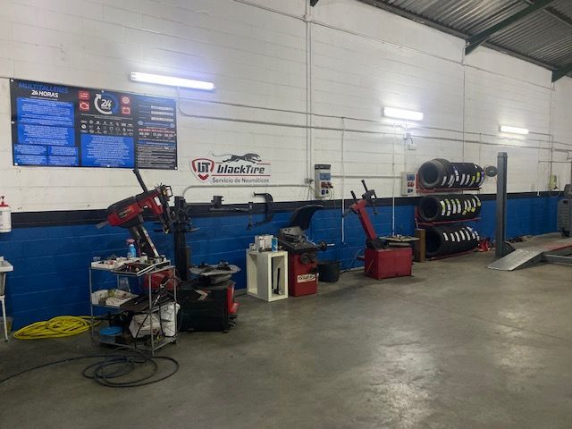 Un garaje con un montón de herramientas y neumáticos en el suelo.