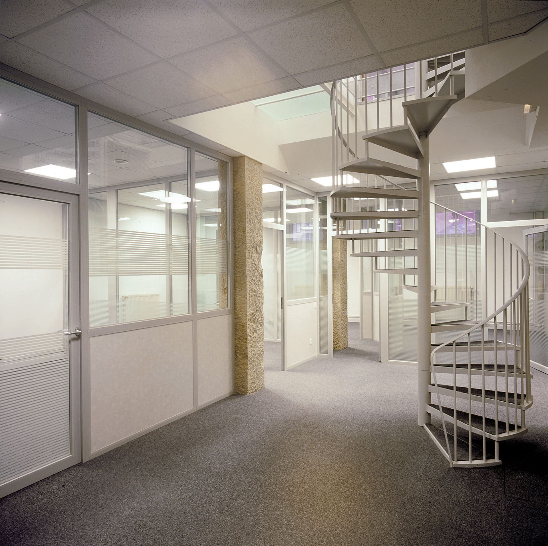 Bureaux aux cloisons vitrées et escalier en colimaçon