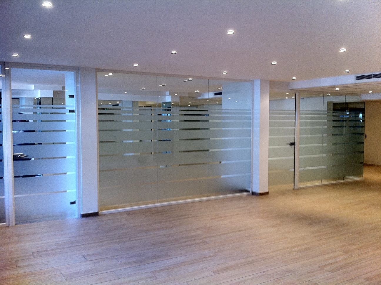 Grandes vitres délimitant chaque bureau à l'intérieur d'un immeuble