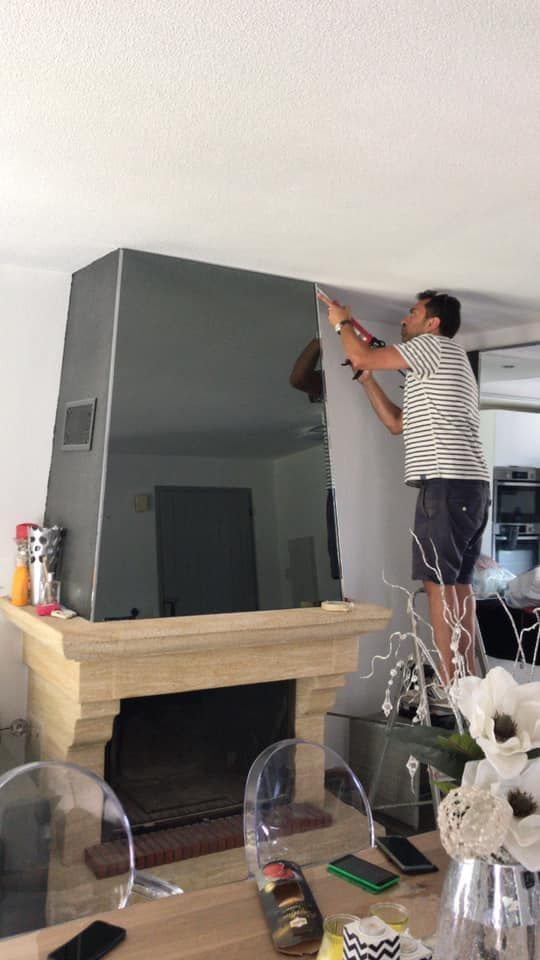 Une personne sur un escabeau en train de placer un joint entre la cheminée et le plafond