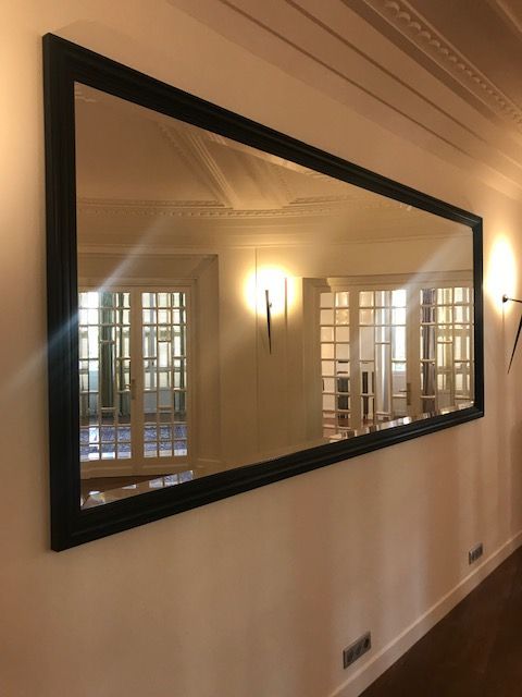 Grand miroir au cadre noir accroché au mur