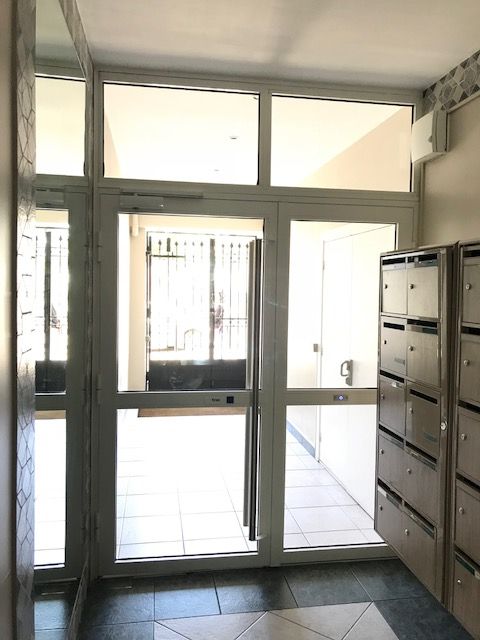 Portes vitrées à l'intérieur d'un hall d'immeuble à proximité des boîtes aux lettres