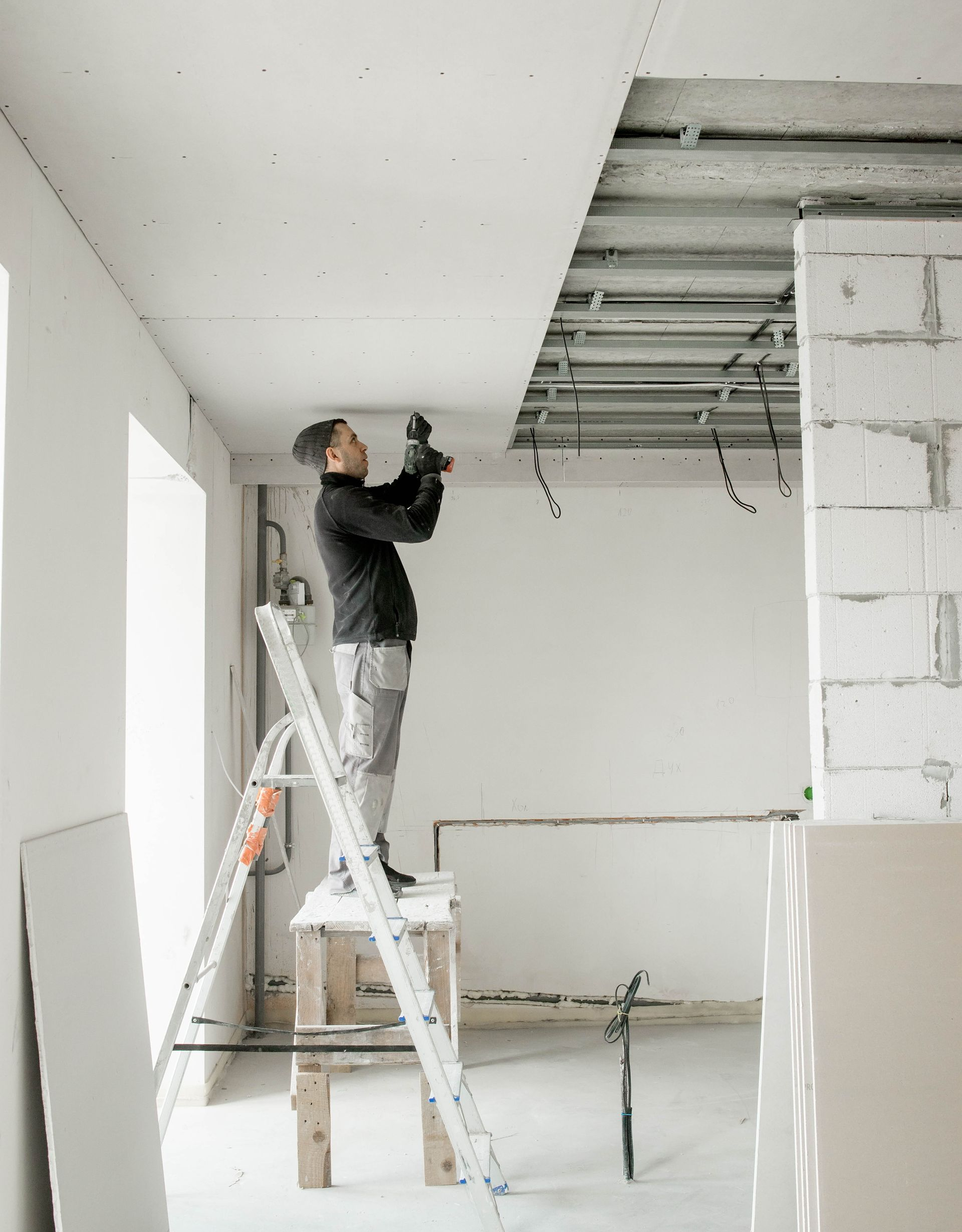 Un homme monté sur une table levant les bras au plafond avec un matériel