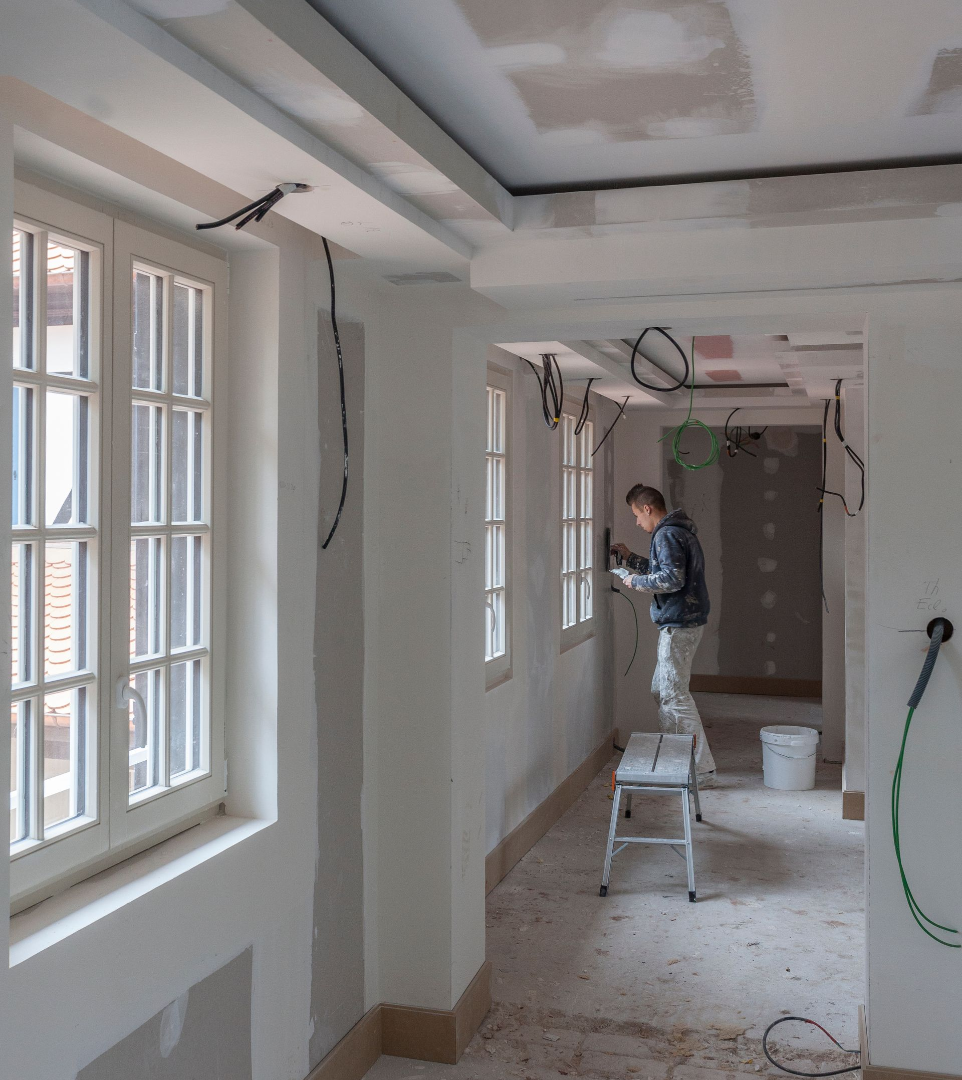 Un monsieur travaille sur le mur dans un couloir