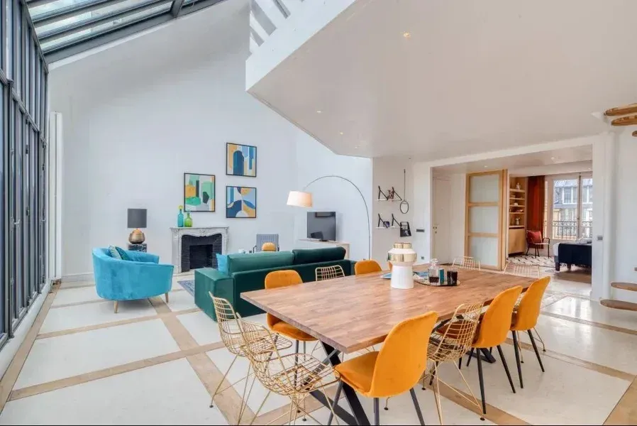 Salon moderne à aire ouverte avec un coin repas, un canapé turquoise et des chaises orange.