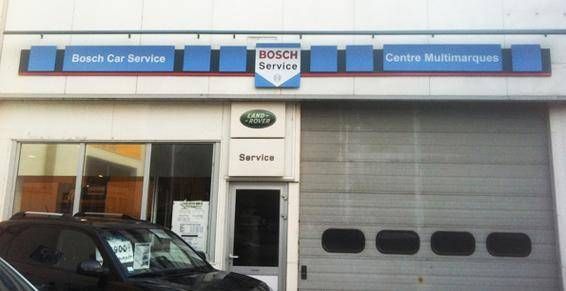 Façade d’un centre Bosch Car Service avec une enseigne bleue et une porte de garage grise fermée