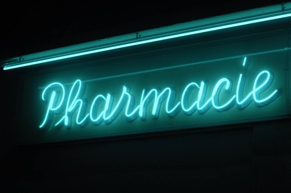 Enseigne « Pharmacie » bleu néon illuminée sur la façade sombre d’un commerce, la nuit